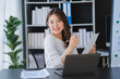 © Kritdanai - Beautiful Asian businesswoman working on a desk with a laptop with a smiling face while looking at the document received in the office.