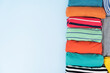 © tatomm - close up of rolled colorful t shirt clothes on blue table background, travel concept
