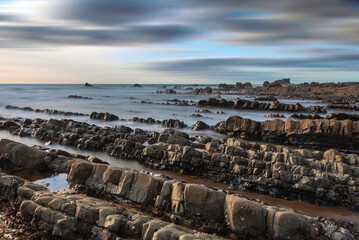 Wall Mural - Beautiful sunset landscape image of Welcome Mouth Beach in Devon England with beautiful rock formations