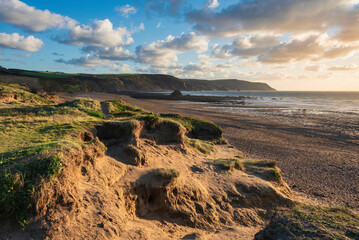 Wall Mural - Stunning Summer sunset landscape image of Widemouth Bay in Devon England with golden hour light on beach