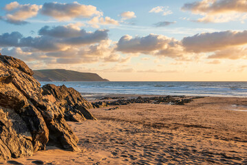 Wall Mural - Stunning Summer sunset landscape image of Widemouth Bay in Devon England with golden hour light on beach