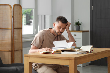 Canvas Print - Sleepy man studying at wooden table indoors