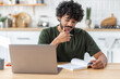 © kucherav - Distance learning, online education. Portrait of smiling young male freelancer or student viewing webinar or training sitting at home, writes notes in a notebook. Asian man using laptop computer