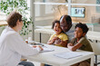 © AnnaStills - Happy little children sitting together with their dad at table and talking to pediatrist at office