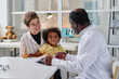 © AnnaStills - Young woman visiting pediatrician with her little son, they sitting at table and talking to doctor