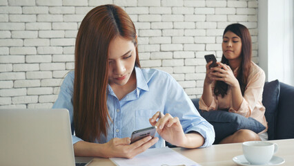 Wall Mural - Two businesswomen team meeting using laptop at company office desk. Two young Female freelance reading financial graph charts Planning analyzing marketing data. Asian people team working office firm.