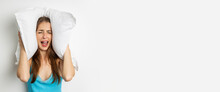 Screaming Young Woman Covers Her Ears With A Pillow On A White Background. Banner