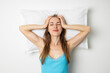 © Alex - Smiling young woman lies on a pillow on a white background. top view, flat lay