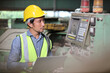 © feeling lucky - Technician engineer or worker in protective uniform standing and using computer while controlling operation or checking industry machine process with hardhat  at heavy industry manufacturing factory