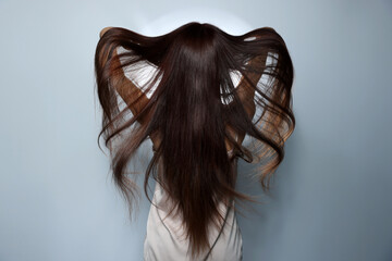 Fashion model with strong healthy hair posing in studio, back view