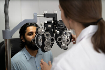 An eye doctor examines a male patient in a clinic with modern equipment.