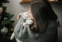 Merry Christmas! Woman In Cozy Sweater Hugging Cute Cat Near Stylish Christmas Tree With Vintage Baubles. Pet And Winter Holidays. Adorable Kitty And Happy Woman Cuddling In Festive Room