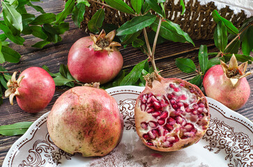 Wall Mural - group of pomegranates on a rustic wooden table. A pomegranate cut into two parts inside a vintage plate