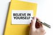© Volha - Wooman holding BELIEVE IN YOURSELF text card