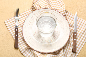 Wall Mural - Plate, cutlery, napkin and glass of water on beige background. Anorexia concept