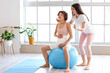 © Pixel-Shot - Young woman and her pregnant wife training with fitball at home