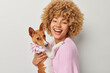 © wayhome.studio  - Positive curly female owner poses with pedigree basenji dog embraces pet expresses love and care wears knitted pink jumper isolated over white background. Domestic animals and veterinary concept