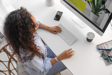 Young African-American woman working with computer at table in office