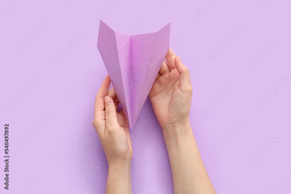 Woman with lilac paper plane on color background