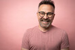 Portrait of mature 50s happy smiling caucasian man dressed in casual redwood color t-shirt with glasses with attractive face isolated on pink studio background
