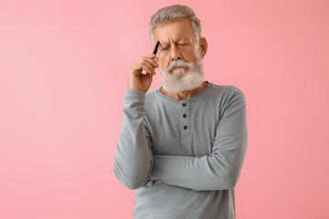 Wall Mural - Thoughtful mature man with pen on pink background