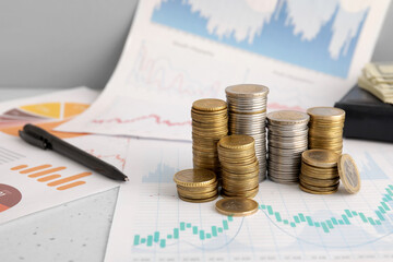 Poster - Stacks of coins and pen on diagrams near grey wall, closeup. Exchange rate concept