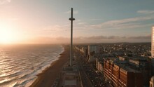 Magical Sunset 4k Aerial Video Of British Airways I360 Viewing Tower Pod With Tourists In Brighton, UK With Sea And Brighton Palace Pier In The Background.
