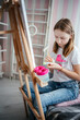 © Анна Молько - Заголовок	a girl in a white T-shirt paints with paints on a canvas on an easel. drawing at home.