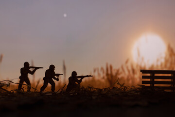 Wall Mural - toy military at war, armed with weapons miniature figurines of soldiers in the field at sunset, army service concept