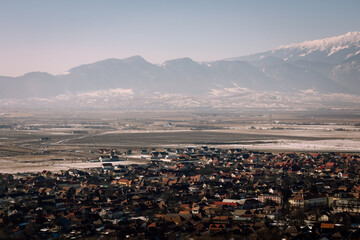 Panoramic view over the ski slope Poiana Brasov ski resort in Transylvania, Pine forest covered in snow on winter season,Mountain landscape in winter with the Bucegi Mountains in the background.