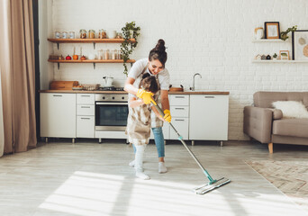 a little daughter and her mom clean the house, a child washes the kitchen floor, a cute little helper girl cleans the floor with a mop, a happy family cleans the room.