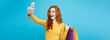 Shopping Concept - Close up Portrait young beautiful attractive redhair girl smiling looking at camera with white shopping bag and selfie. Blue Pastel Background. Copy space
