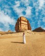 Vertical shot of a man standing in front of the Tomb of Lihyan son of Kuza in Saudi Arabia