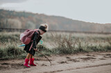 Fototapeta  - Mała dziewczynka z plecakiem rysuje patykiem po ziemi