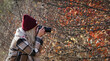 Kobieta fotograf, blond włosy wykonująca zdjęcia przyrody jesienią.