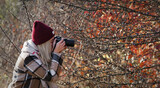 Fototapeta  - Kobieta fotograf, blond włosy wykonująca zdjęcia przyrody jesienią.