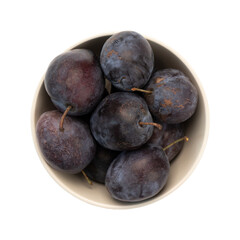 Wall Mural - fresh ripe purple plums in ceramic bowl isolated on white background, top view