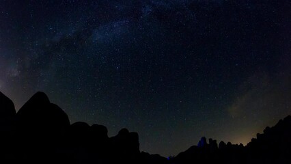 Wall Mural - Lockdown Time Lapse Shot Of Silhouette Rocks Against Sparkling Star Trails At Joshua Tree National Park