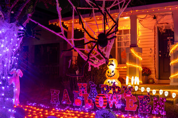 Wall Mural - Glowing outdoor decorations with spiders, pumpkins, ghosts and inscription Happy Halloween orange garlands on the house porch