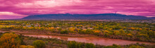 Rio Grand River, Autumn Landscape With Colorful Cottonwood Trees, And Dramatic Pink Stormy Clouds At Sunset Over Albuquerque City Skyline, New Mexico, USA