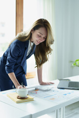 Portrait of a thoughtful Asian businesswoman looking at financial statements and making marketing plans using a computer on her desk