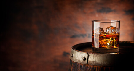 Wall Mural - Glass of whiskey with ice cubes on the old barrel