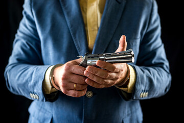 cropped portrait of male bodyguard in tuxedo holding weapon for defense.