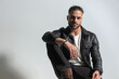 © Viorel Sima - stylish young man wearing black leather jacket posing with elbow on knee