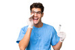 © luismolinero - Young dentist man holding tools over isolated background shouting with mouth wide open