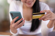 © amnaj - Close-up of woman enjoying the peace of mind of online shopping on mobile using credit card at home.