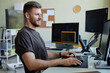 Side view portrait of smiling Caucasian man as computer programmer writing code at office workplace