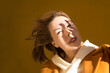 © ulza - a woman in a yellow coat shades her face with her hand from the sun against the background of a yellow wall walks around the city.  copy space.