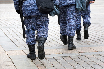 Wall Mural - Legs of soldiers of military forces in camouflage, men walking down the city street