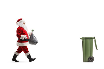 Wall Mural - Full length profile shot of santa claus walking towards a bin and carrying a plastic bag